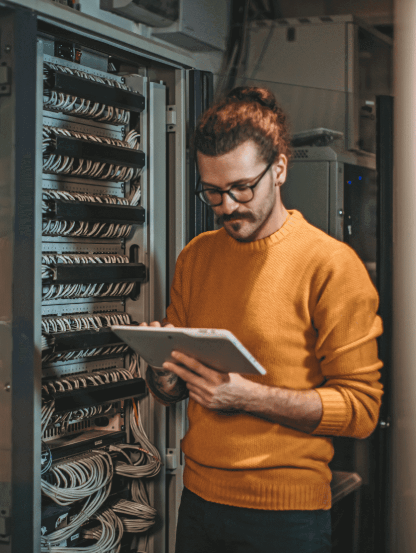 Man looking at tablet next to network cabinet